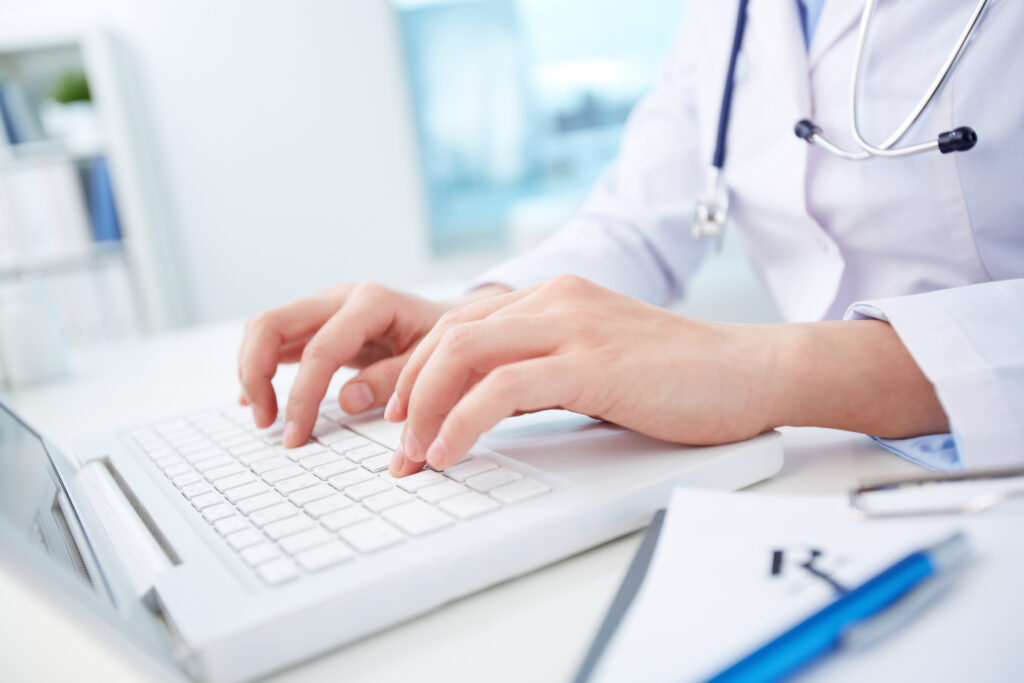 Nahaufnahme einer Ärztin, die medizinische Aufzeichnungen von der DiGA ProHerz über einen Laptop studiert.